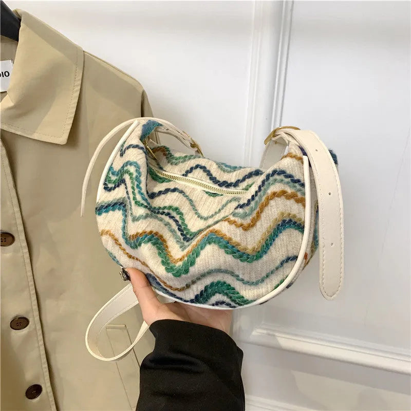 Women's straw woven crossbody bag showing knitted texture and single shoulder strap, shown in corrugated black colour.