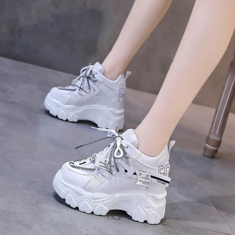 White women's low-top platform sports shoes with cross-strap detail on a rubber sole.