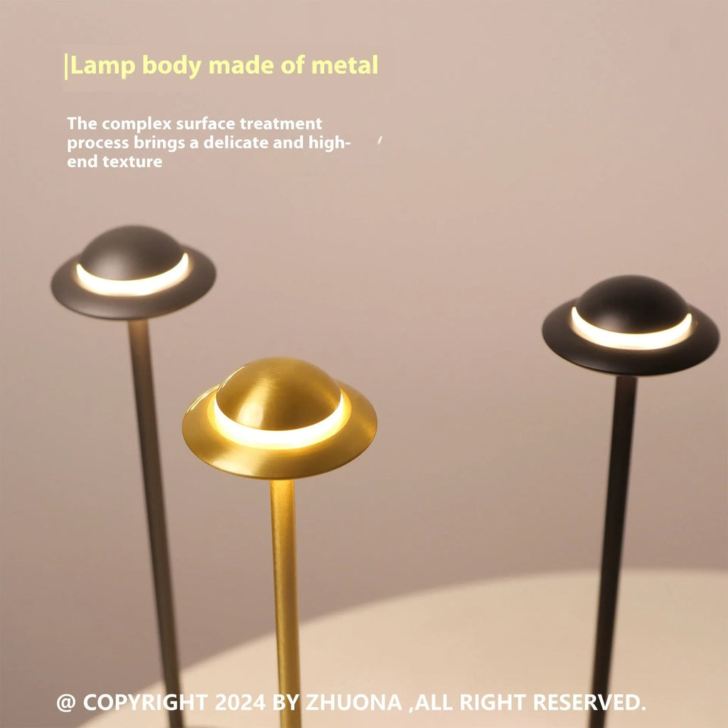 Modern UFO-shaped metal table lamp in black on a wooden desk, showing touch controls and soft glow.