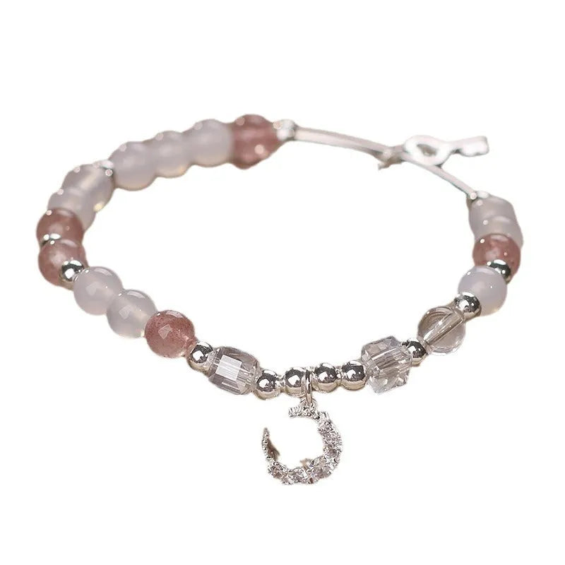 Natural strawberry quartz bracelet with pink cube sugar beads and moon pendant on a flat surface