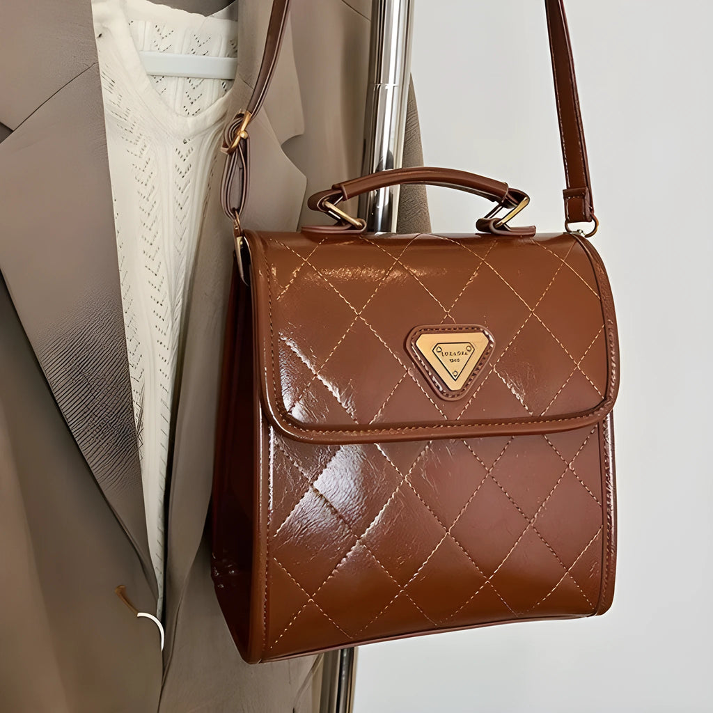 Mini PU backpack in brown with polyester lining, phone pocket, stitching detail, and optional pendant