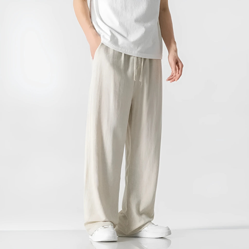 Man wearing beige straight-leg linen bamboo fibre trousers with a drawstring waist and cropped ankle length.