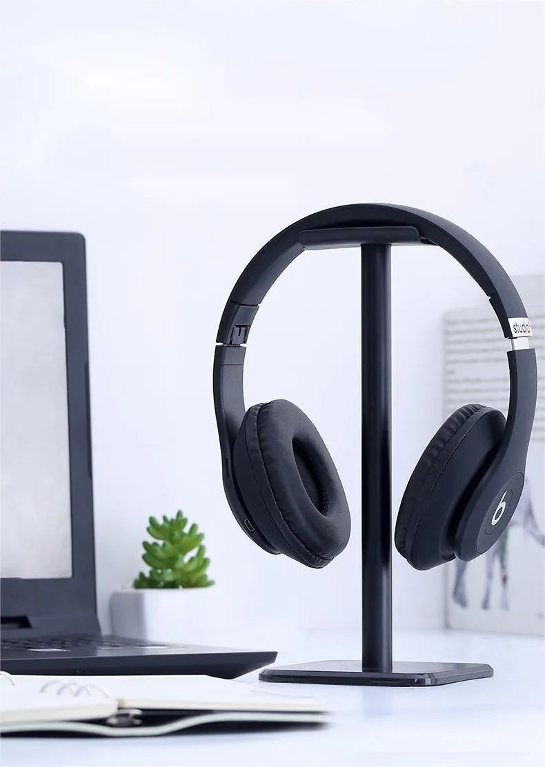 Detachable aluminum alloy headset hanger with TPU rubber cradle, shown in white, pink, and black, fixed to a table.
