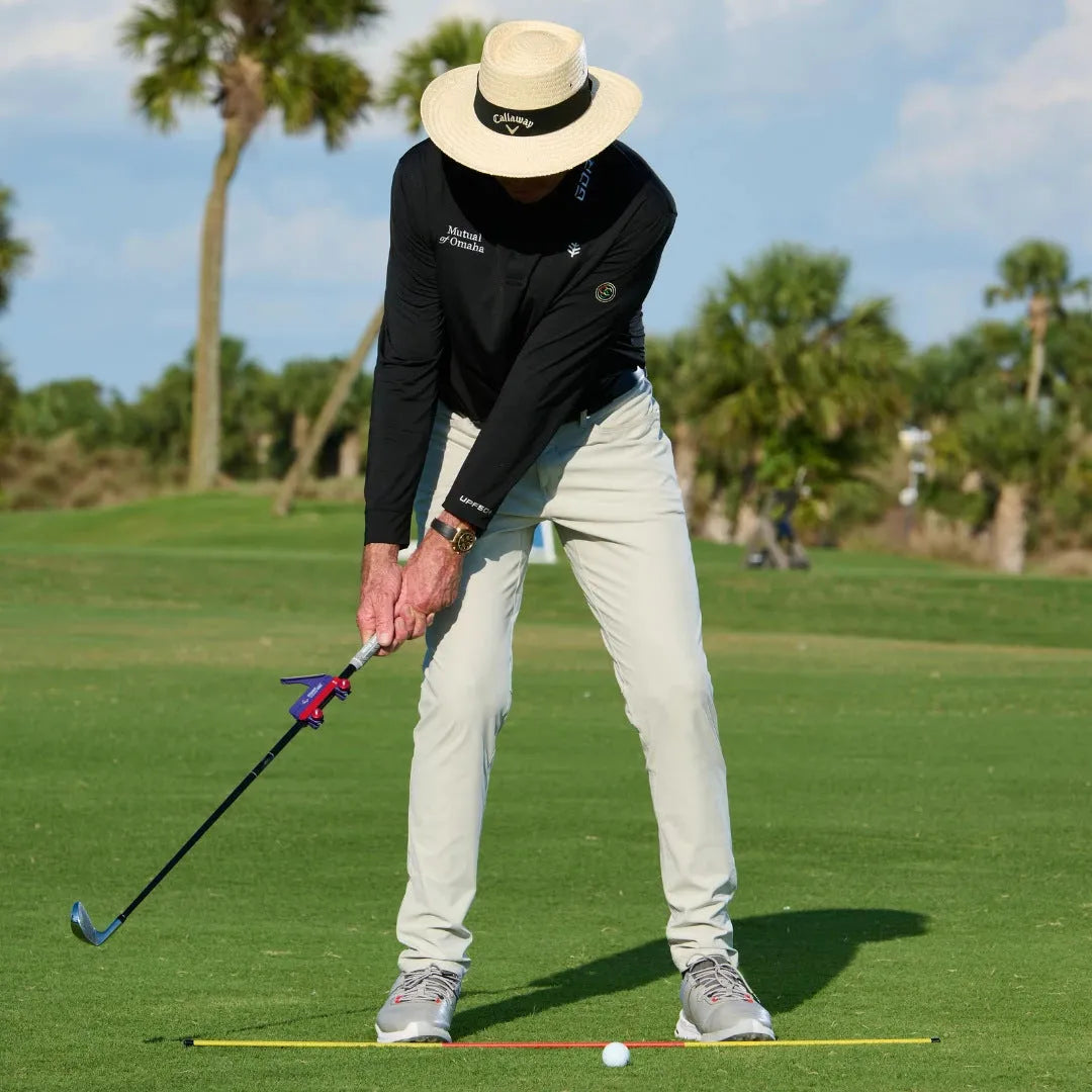 Golf swing plane simulator training aid made of plastic on a practice green.