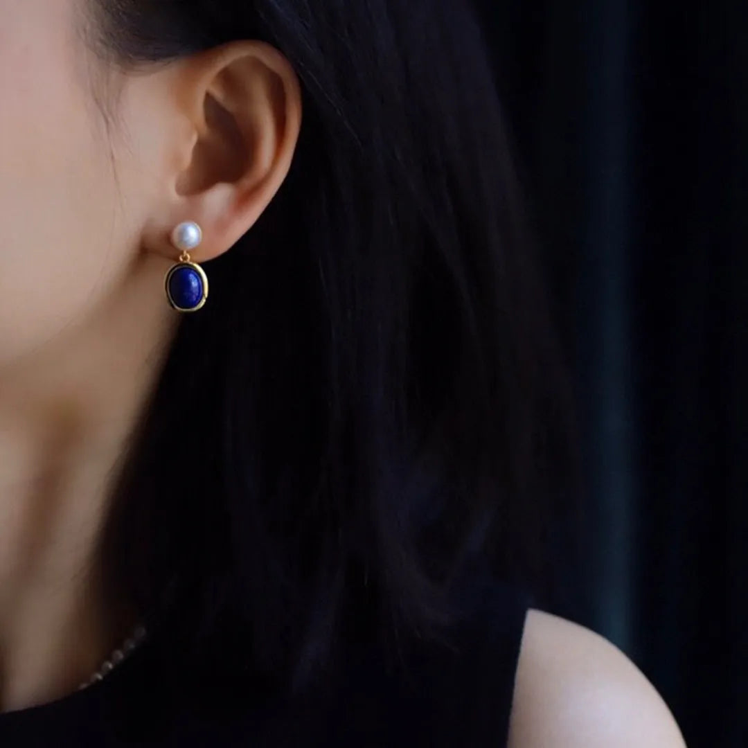 A pair of simple 925 silver earrings featuring a blue lapis lazuli pearl and auspicious pattern detailing.