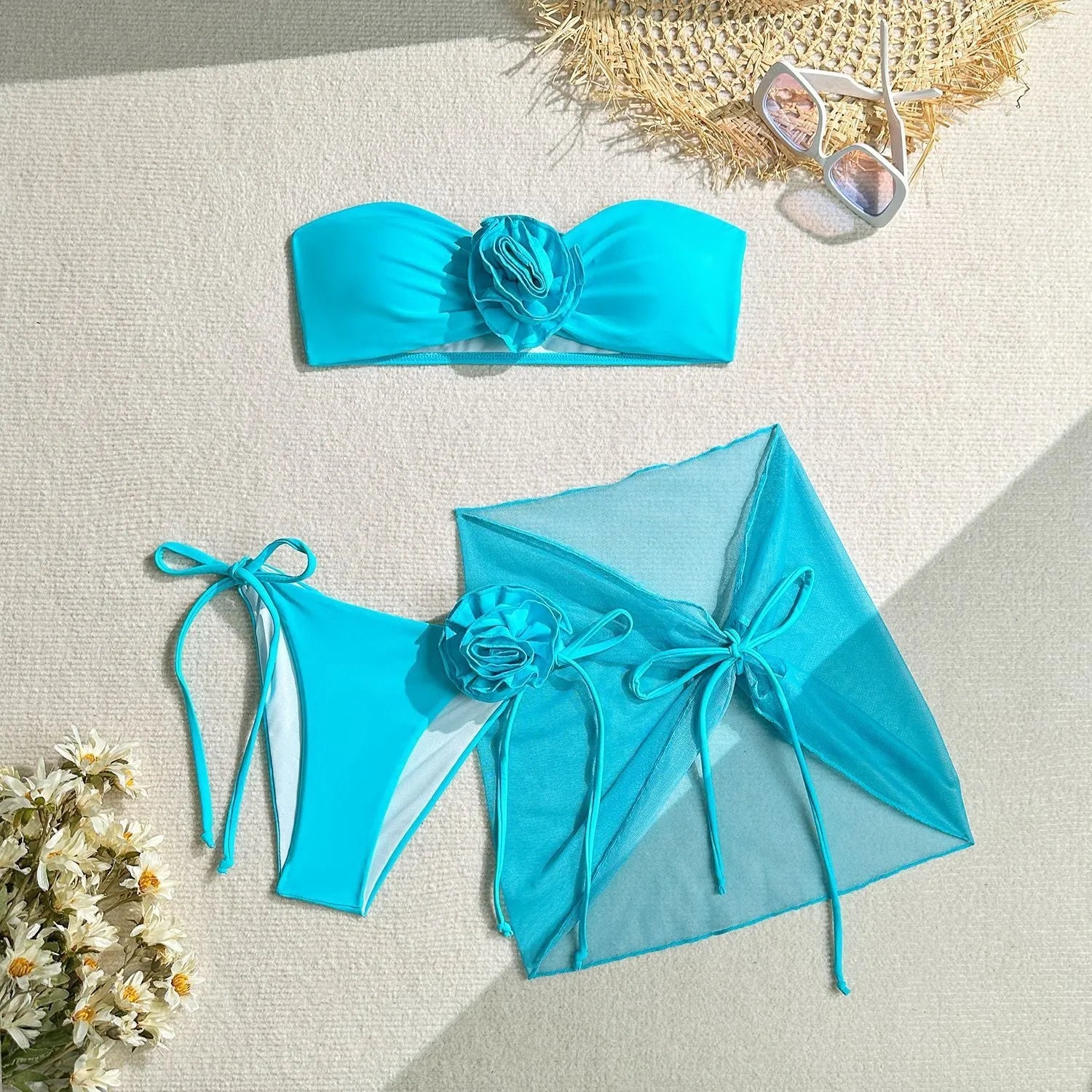 Women's pink swimsuit set with 3D flower tube top, high-waisted bottoms, and separate tie-front skirt laid flat.