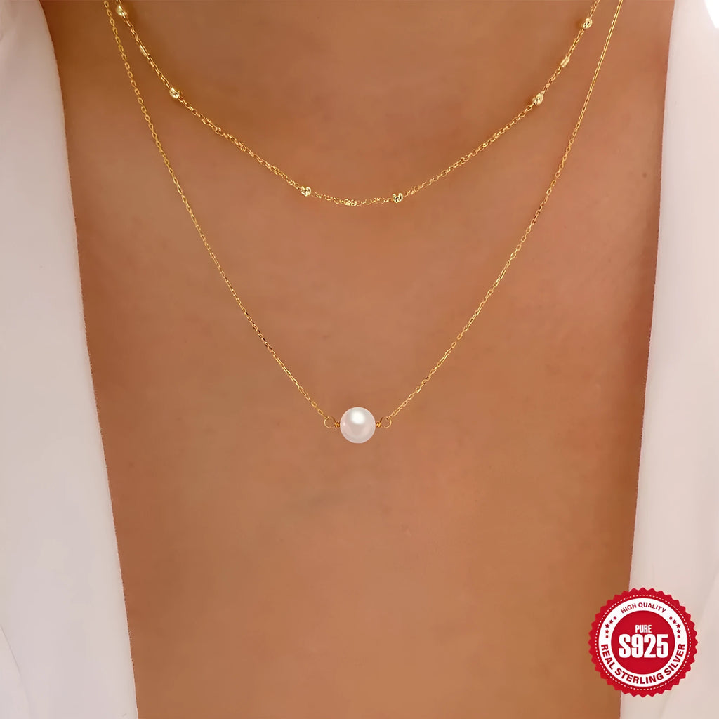 Women's double layer sterling silver necklace with geometric pendant and twin pearls, shown in gold and white gold plating.