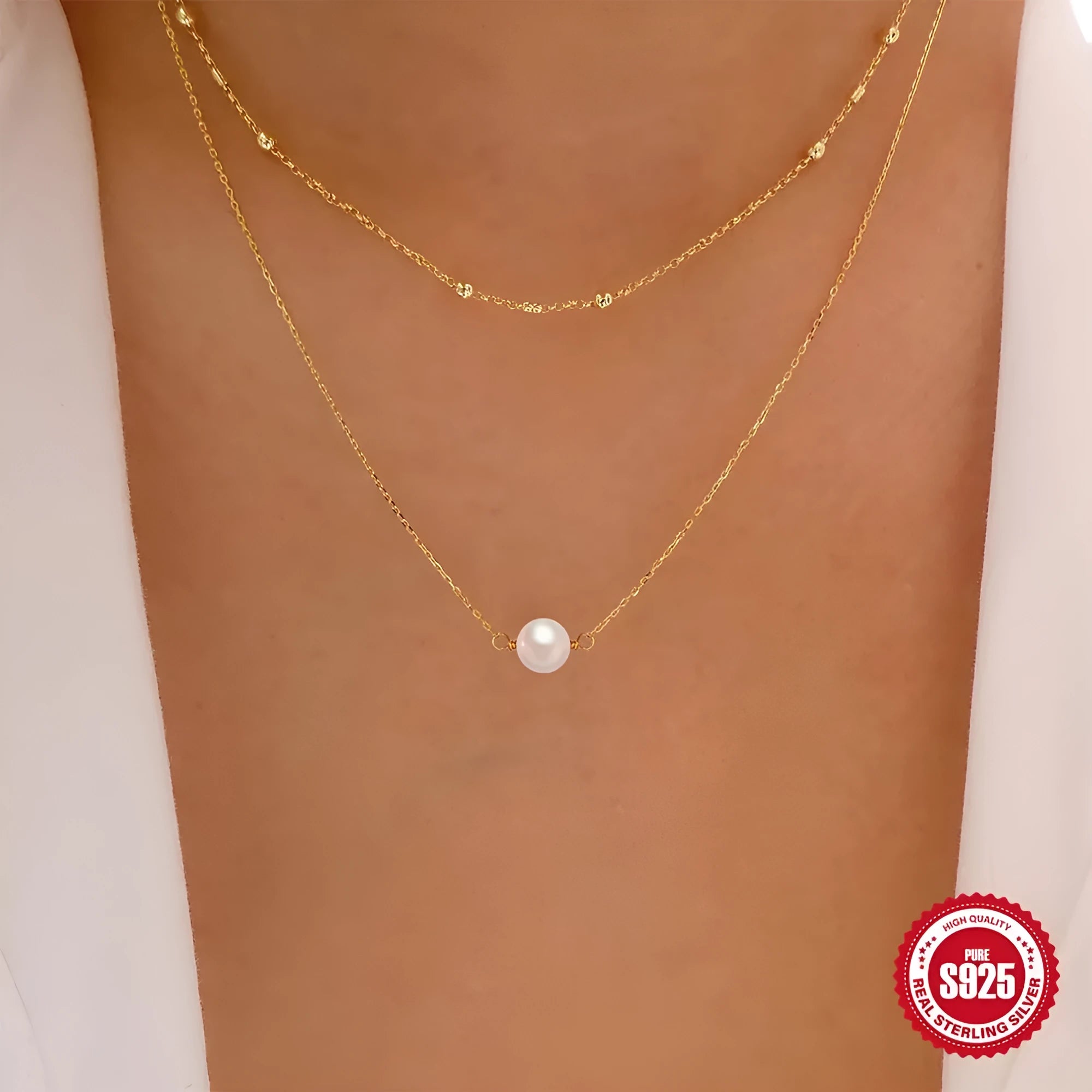 Women's double layer sterling silver necklace with geometric pendant and twin pearls, shown in gold and white gold plating.
