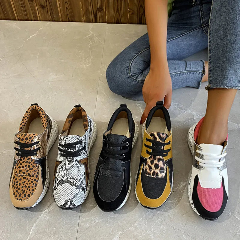 Women's black suede casual sneakers with a low wedge heel on a wooden floor.