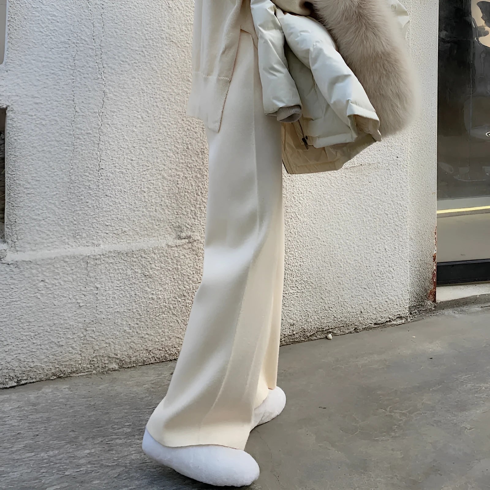Women's cream white high-waisted wide-leg knitted trousers with a straight leg and drooping hem.