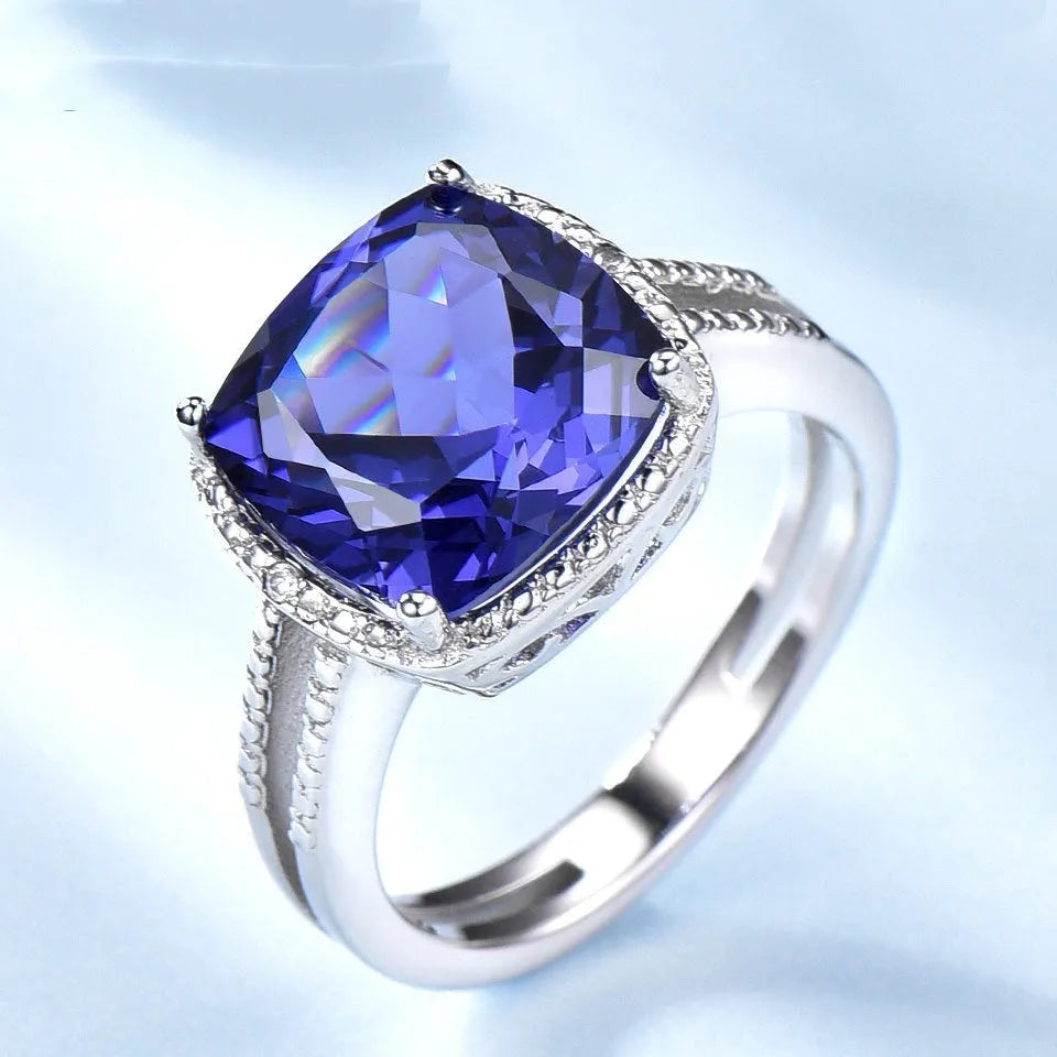 A sterling silver ring for women with a bright blue tanzanite stone, shown on a hand.