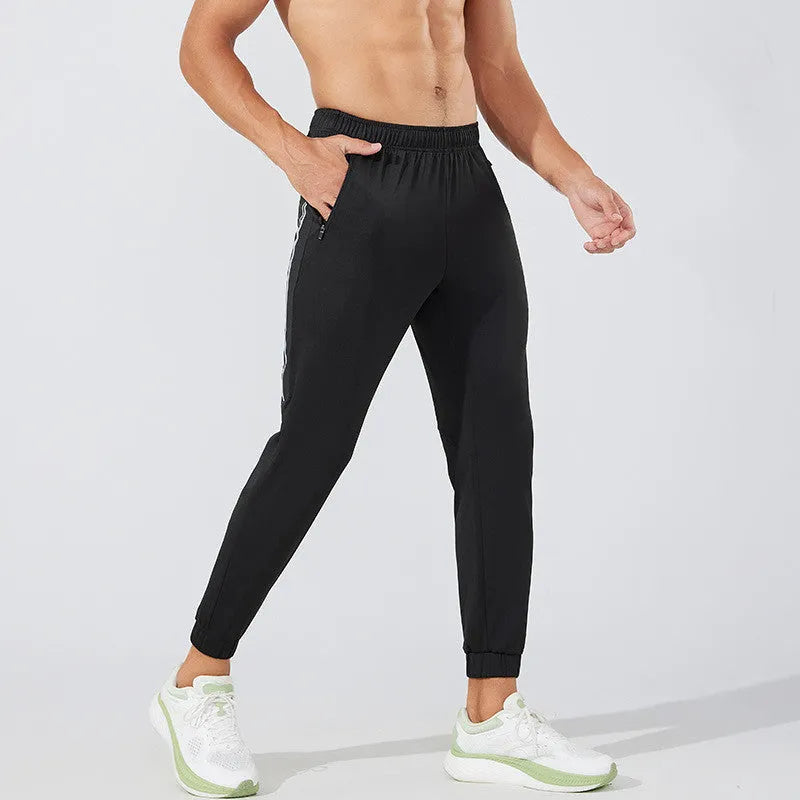 Black men's running trousers with a mid waist, laid flat to show the trousers length and sporty design.