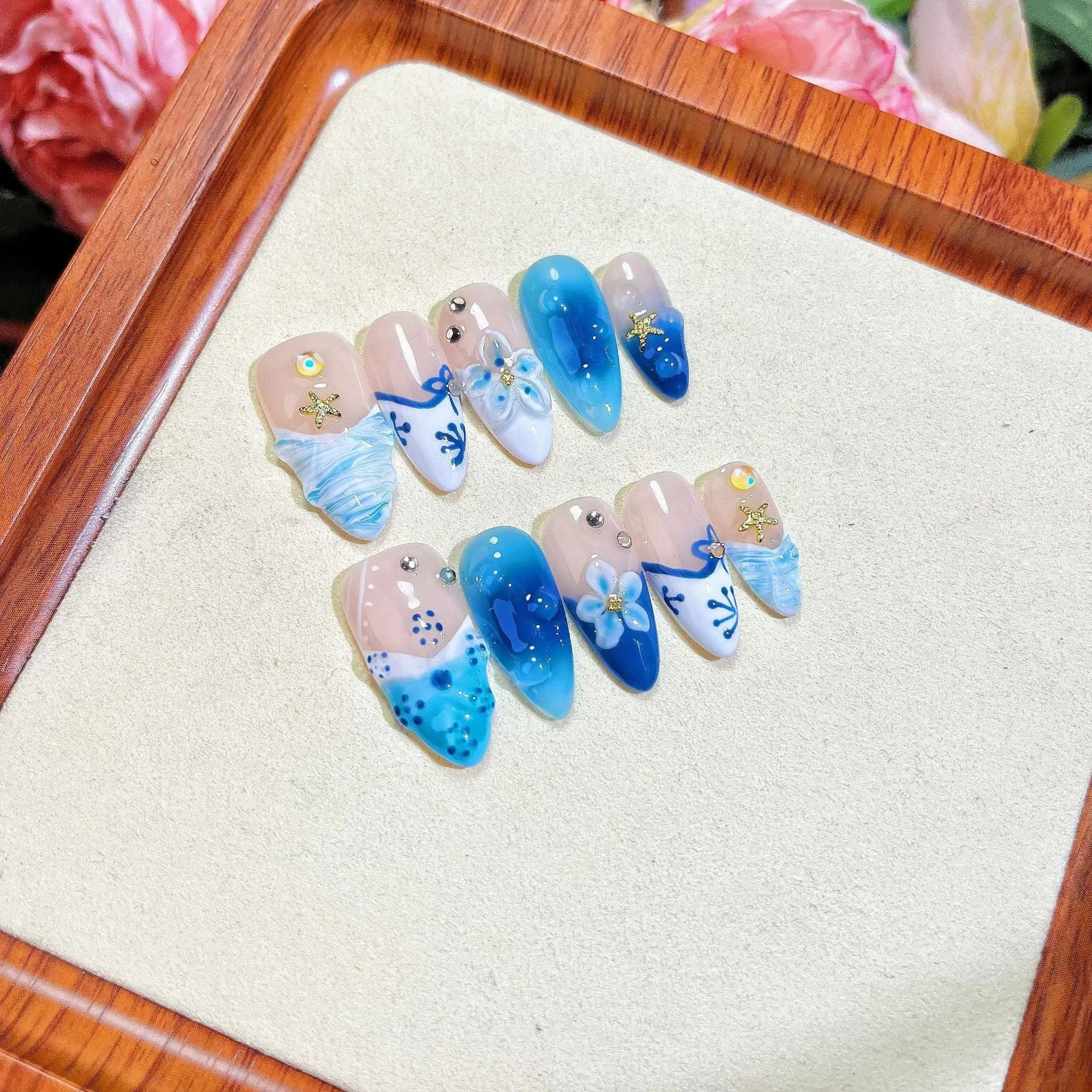 Blue hand-painted carved plastic fake nails on a clear background.