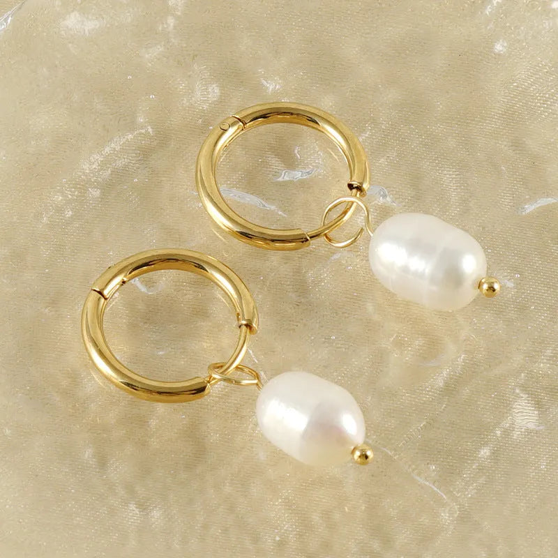 Gold geometric drop earrings with a central freshwater pearl on hypoallergenic posts.