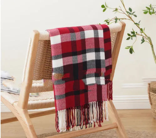 Acrylic chenille plaid throw blanket with tassel trim in gray and white geometric pattern on sofa