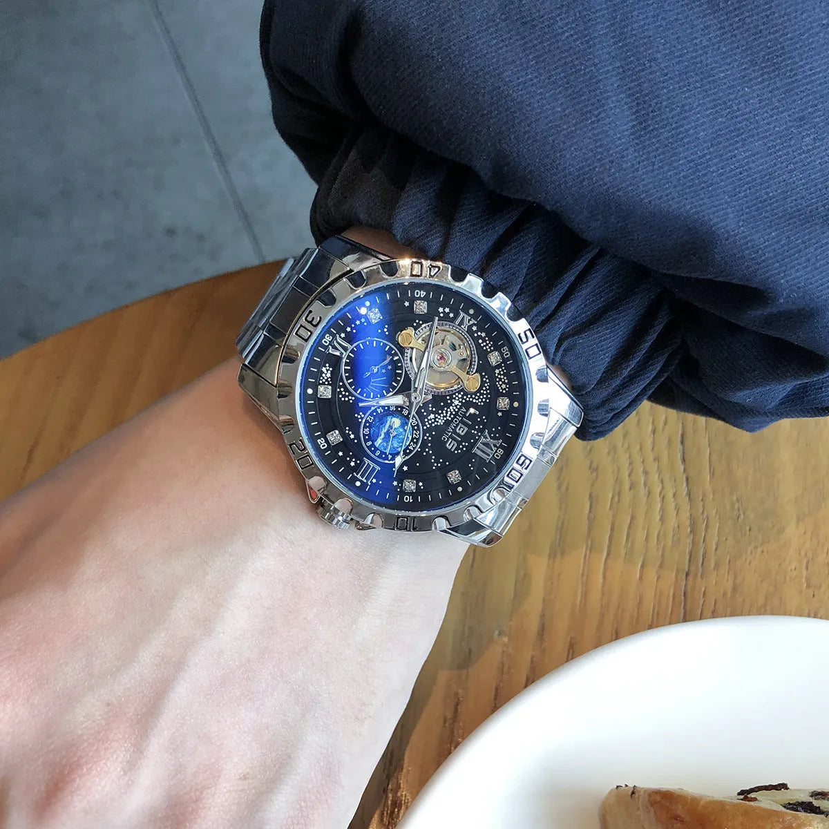 Silver case men's automatic watch with black dial, luminous hands, and brown leather strap.