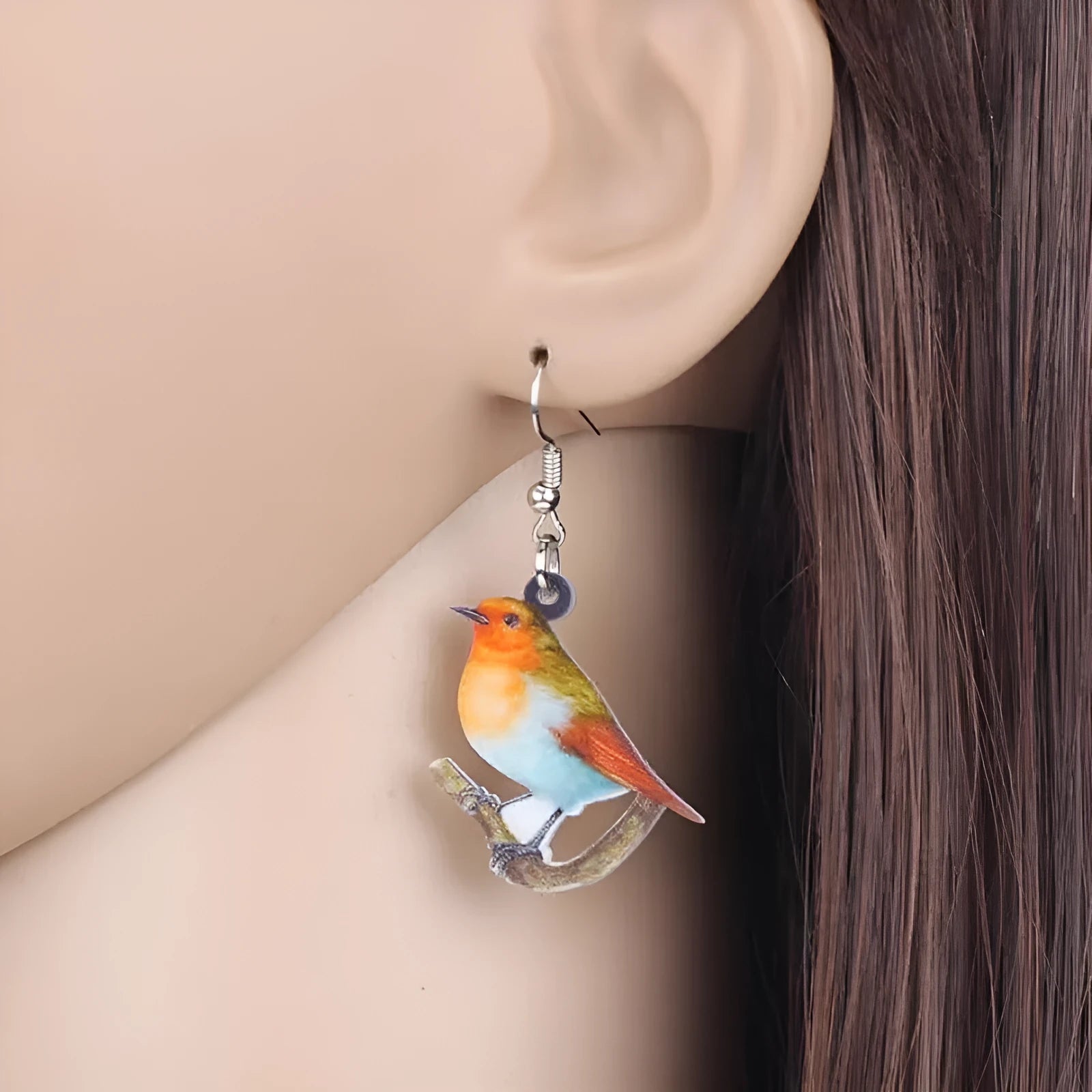 A pair of blue, white, and black acrylic drop earrings featuring a detailed Blue Tit bird and geometric snake patterns on a white background.
