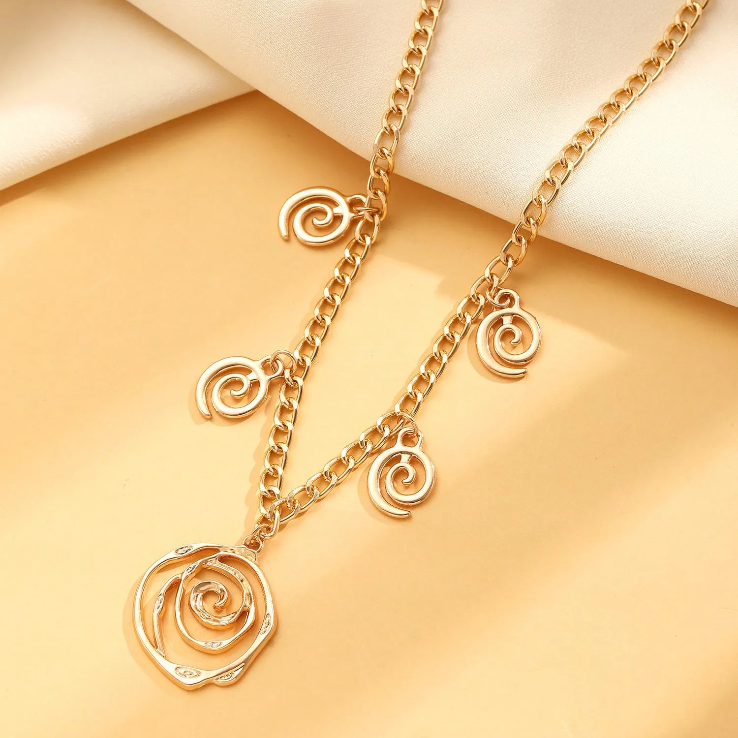 Spiral donut design women's jewellery set showing matching necklace, bracelet, and ear hooks in gold electroplated finish