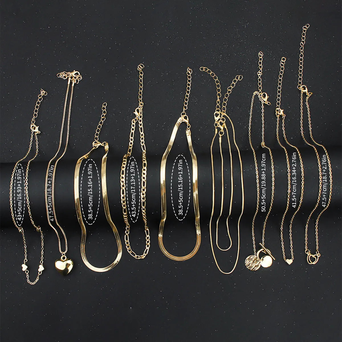 Set of ten gold-coloured women's necklaces with snake bone chains and alloy pendants on a white background.