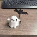 Miniature white ghost dog walking statue holding a small black bat, resin Halloween ornament