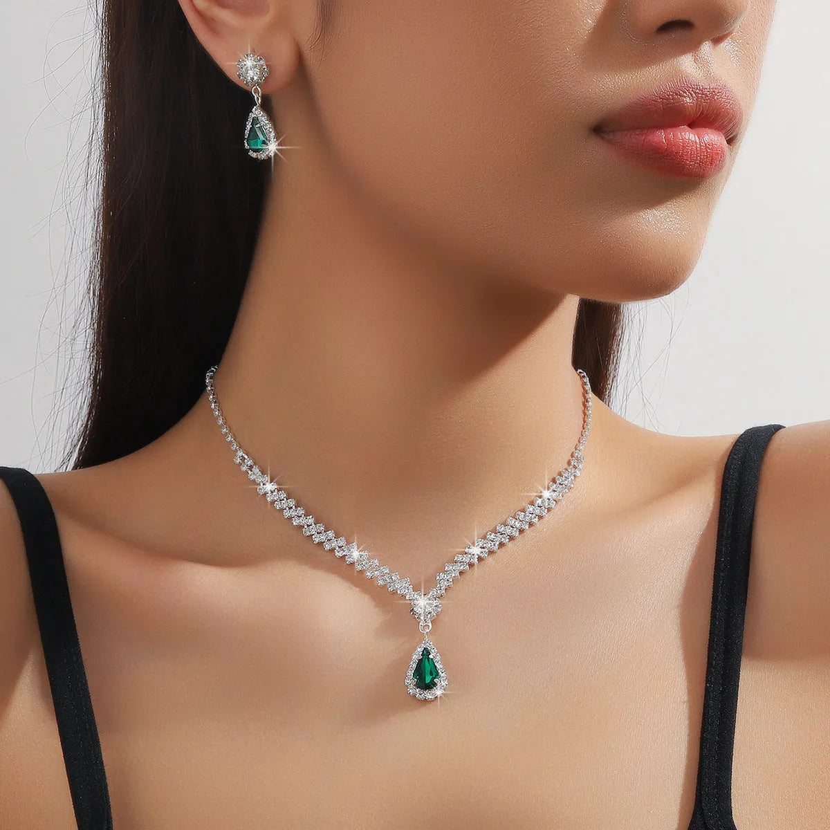 Women's blue claw chain necklace and drop rhinestone earrings set on white background.