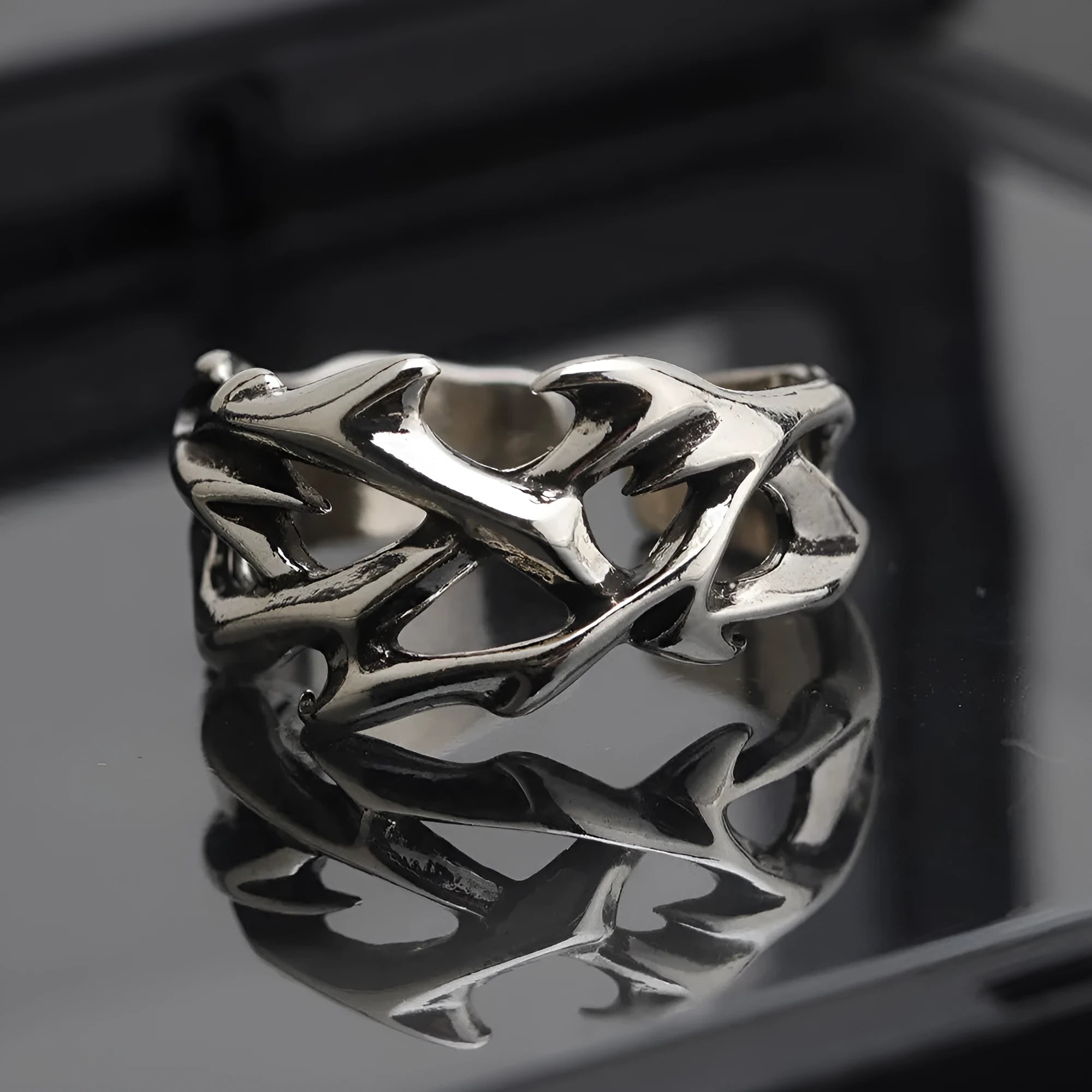Copper geometric ring with thorn and flower design on a finger, showing adjustable opening.