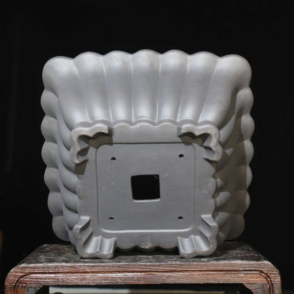 Square purple sand ceramic bonsai pot with du xiliang glaze on a desktop.