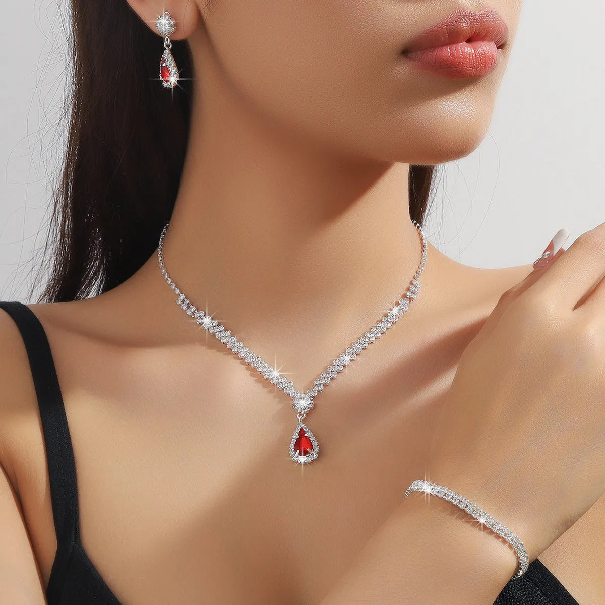Women's blue claw chain necklace and drop rhinestone earrings set on white background.