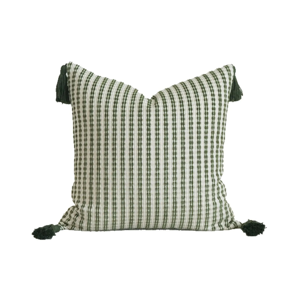 Green striped and botanical pattern decorative pillow with tassels on a bed.
