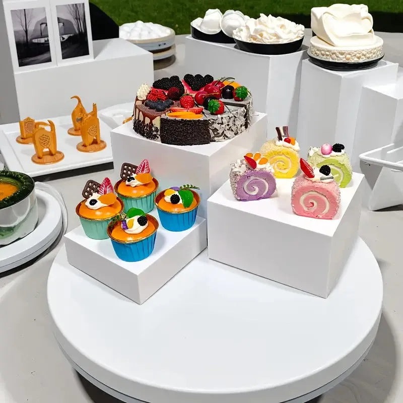 White plastic cube-shaped dessert display stand with multiple tiers for cupcakes and pastries.