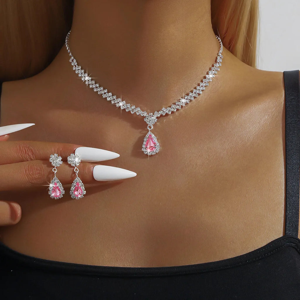 Women's blue claw chain necklace and drop rhinestone earrings set on white background.