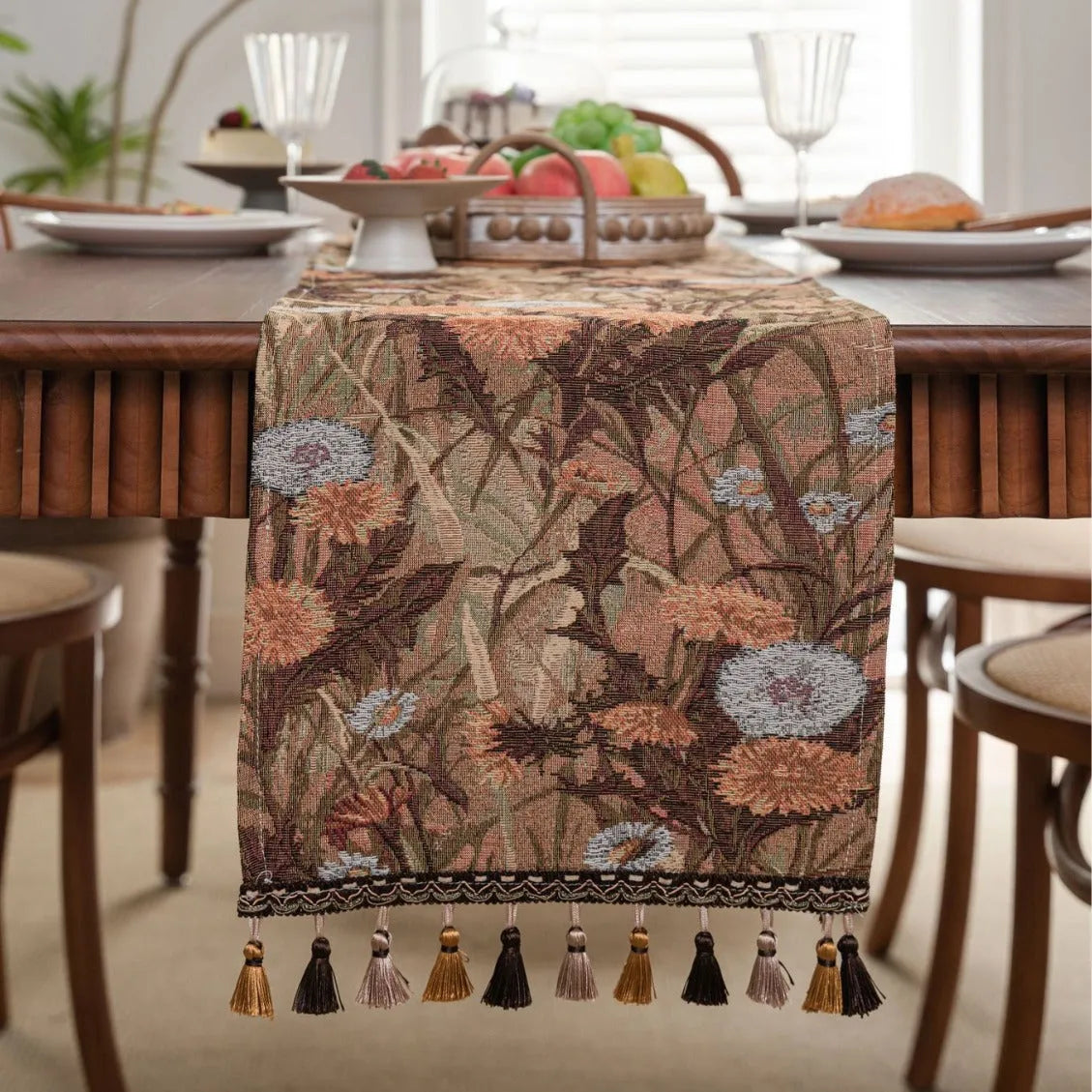 Beige jacquard table runner with floral pattern and long tassels draped over a wooden wedding table.