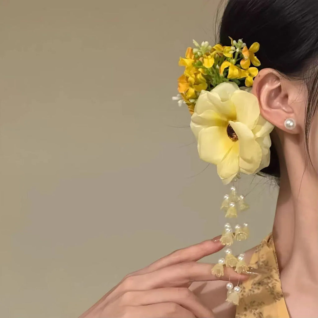 Handmade yellow floral hair clip with pearl beads and a long white tassel on a side-clip grip.