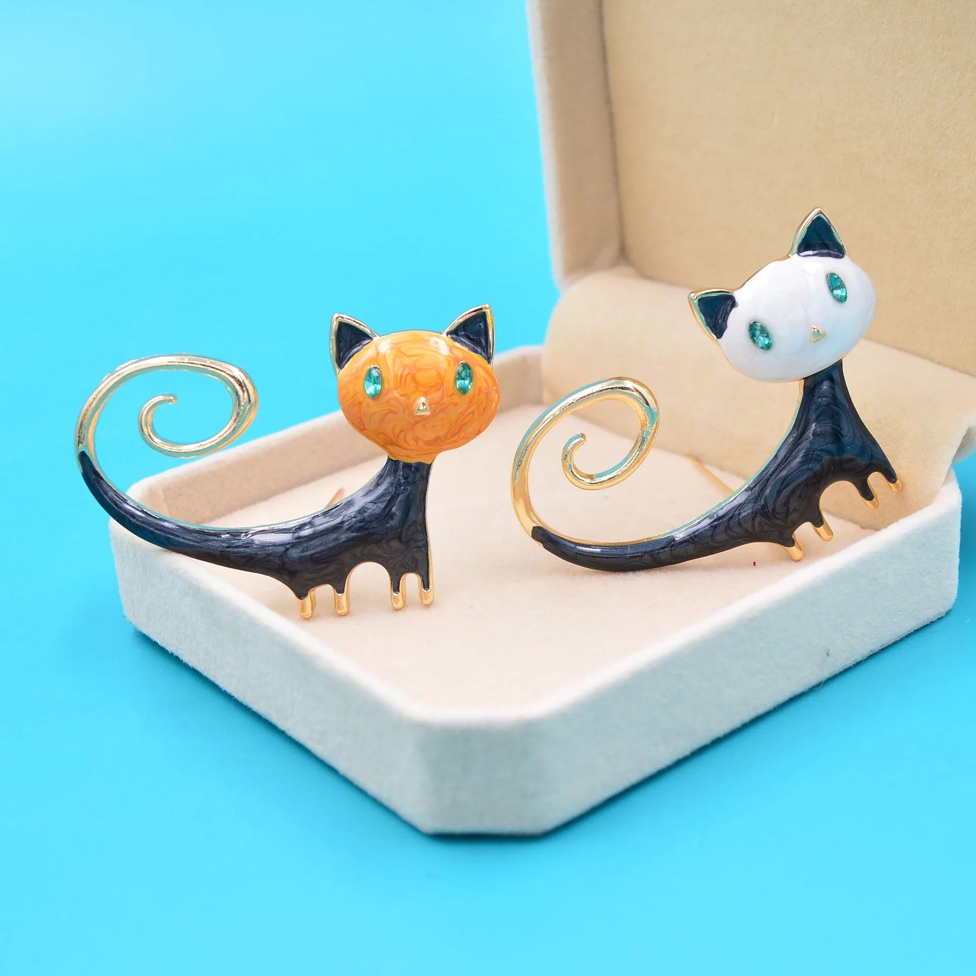 Orange and white alloy cat brooch with painted tail detail and pin fastener.