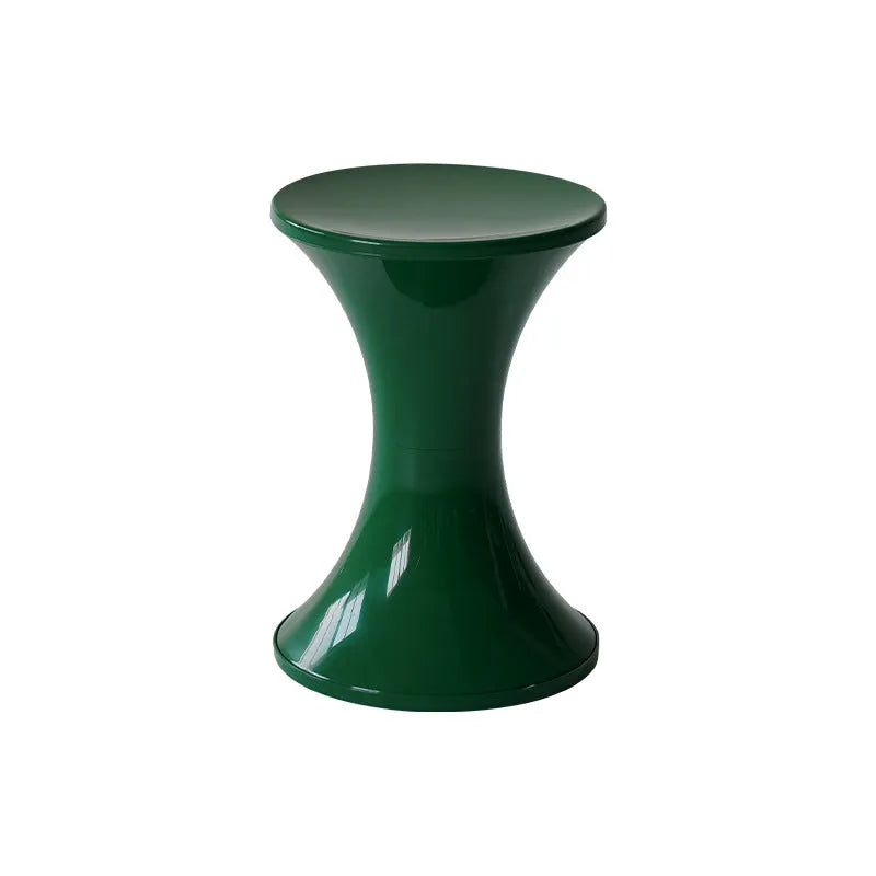 A green plastic hourglass-shaped shoe changing stool on a wooden floor.