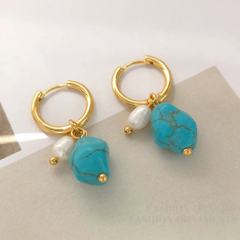 A pair of geometric copper earring clips with turquoise stones and cultured pearls, one short and one long.