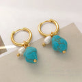 A pair of geometric copper earring clips with turquoise stones and cultured pearls, one short and one long.