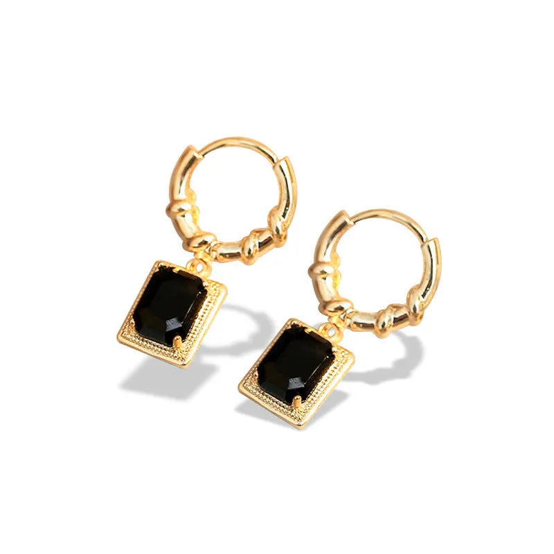 A pair of black geometric quadrilateral earrings with zircon stones on copper settings, shown against a plain background.