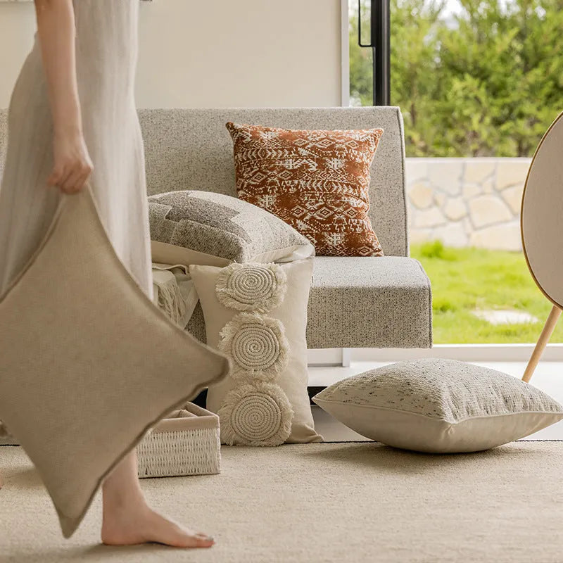 A square solid-colour cushion pillow on a sofa, showing its plain edge detail.