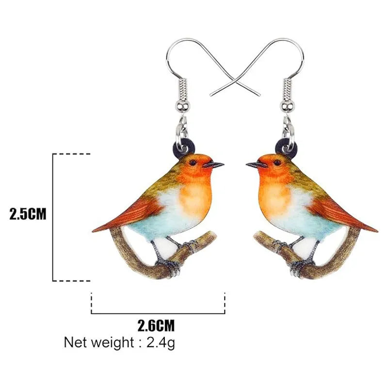 A pair of blue, white, and black acrylic drop earrings featuring a detailed Blue Tit bird and geometric snake patterns on a white background.