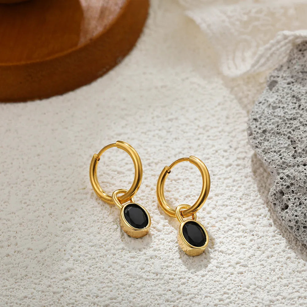 Close-up of women's retro-style copper earrings featuring a single oval-cut zircon stone in an emerald green colour.