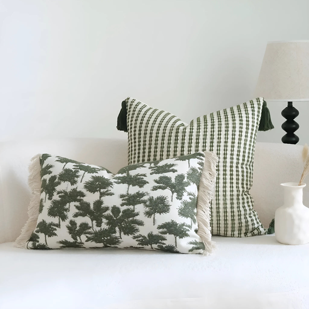 Green cotton and linen hotel pillow with botanical pattern and tassel trim on a bed display.