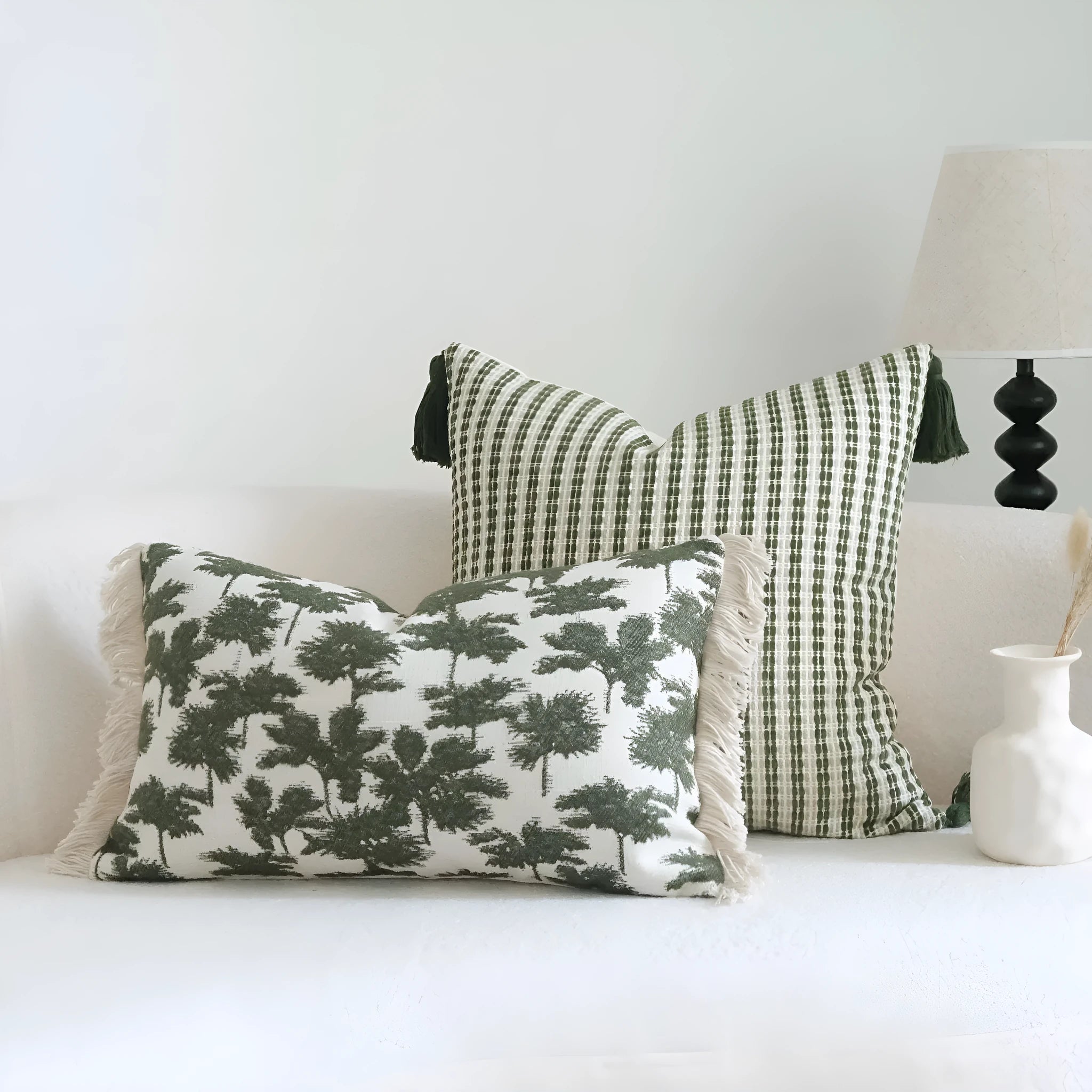Green cotton and linen hotel pillow with botanical pattern and tassel trim on a bed display.