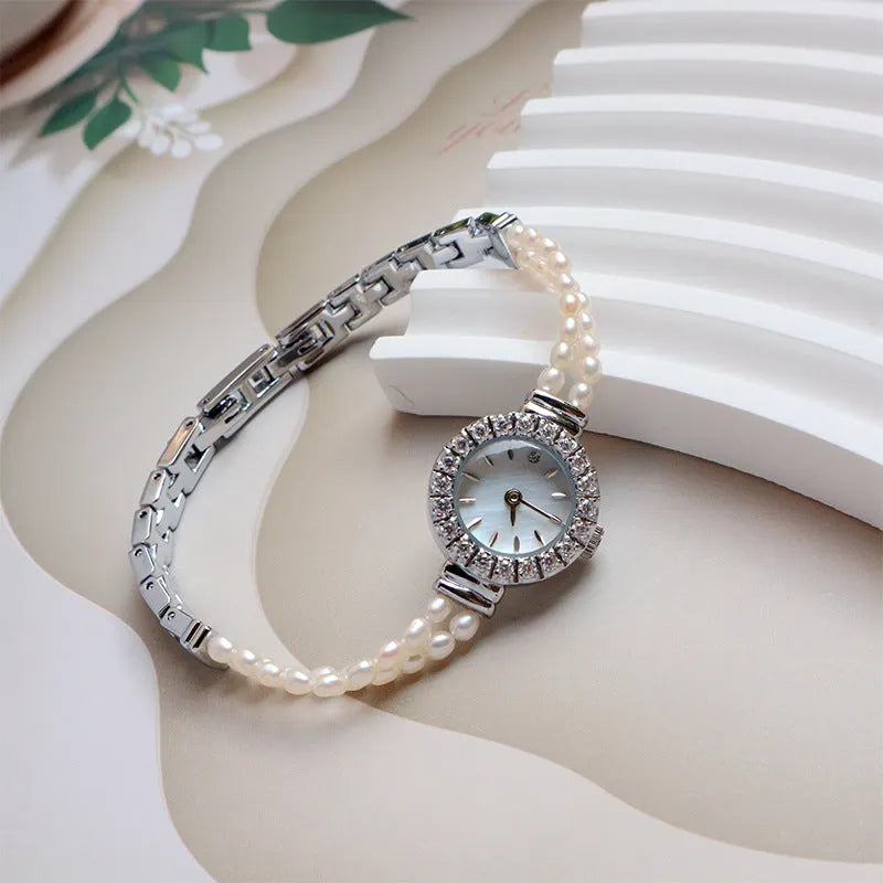Light gold women's freshwater pearl bracelet watch with round dial on stainless steel strap.