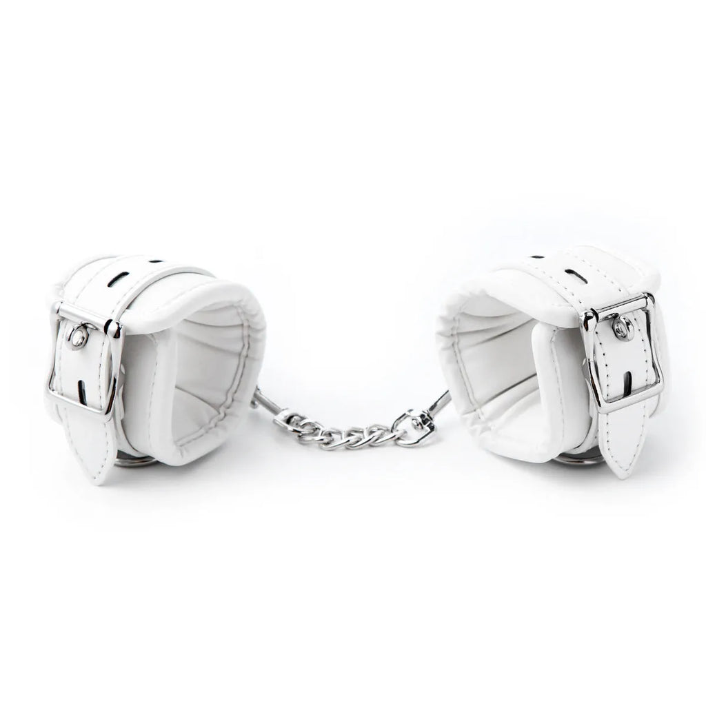 White PU sponge bondage set showing handcuffs, foot cuffs, and a neck scarf arranged together.