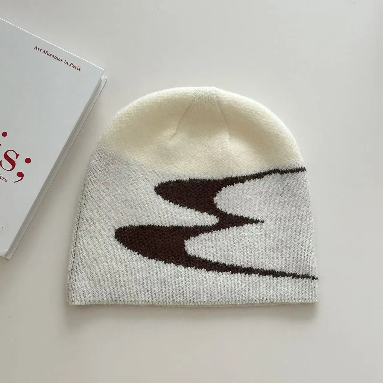 A knitted acrylic beanie hat in black, shown on a model, for autumn and winter wear.
