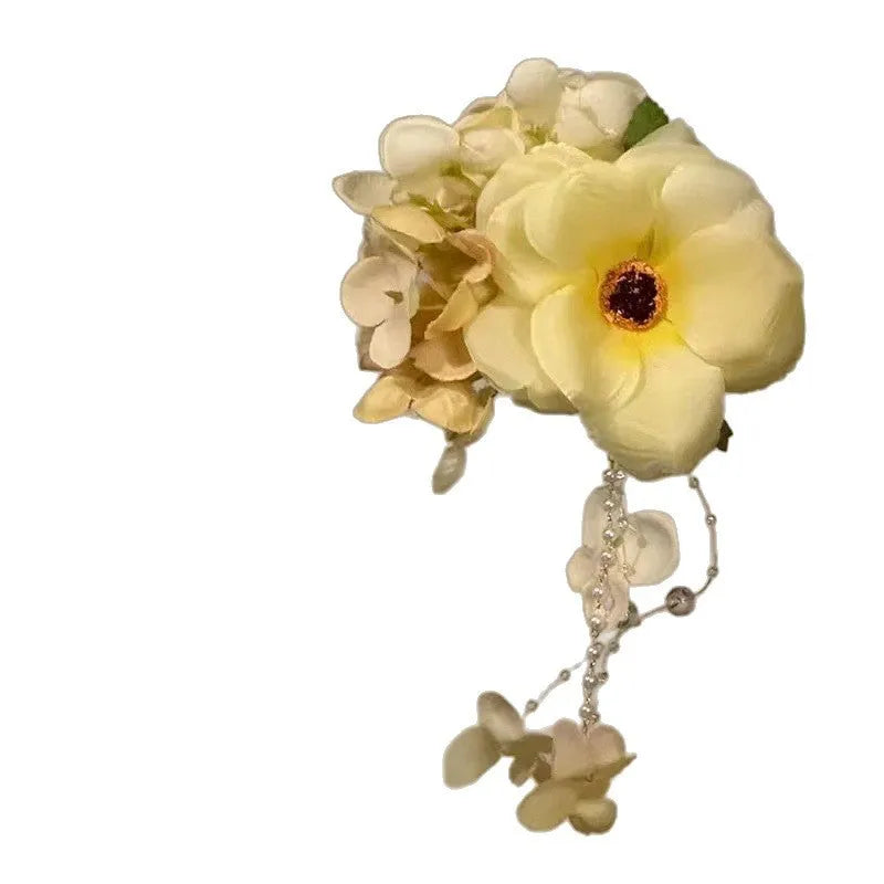 Handmade yellow floral hair clip with pearl beads and a long white tassel on a side-clip grip.