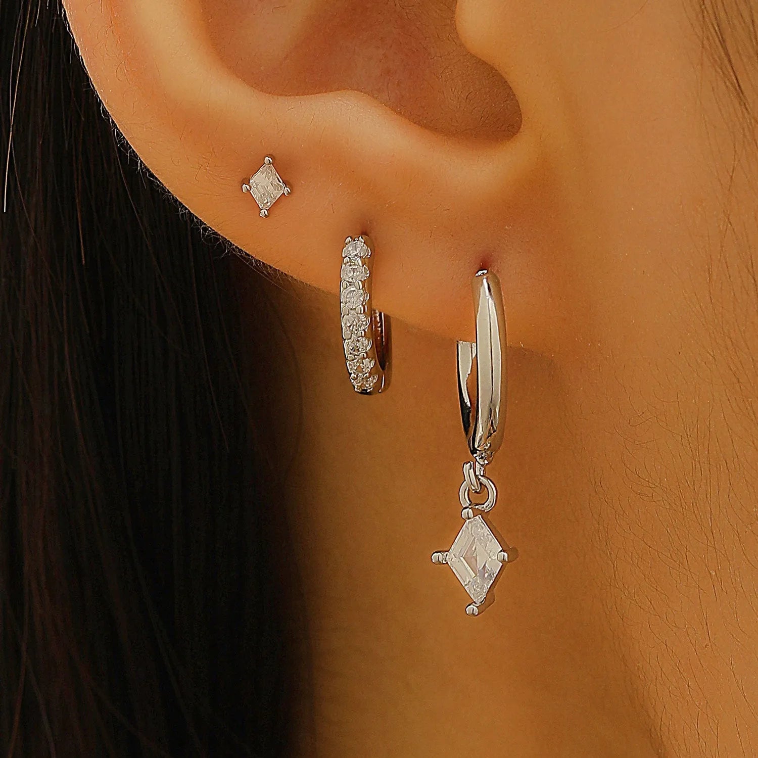 Ladies three-piece earring set with geometric zircon designs in gold and white colours showing pendant, stud, and clip styles