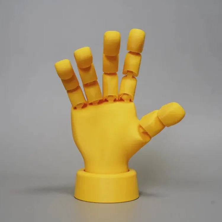 Yellow PLA movable joint hand prop ornament on a flat surface, showing articulated fingers.