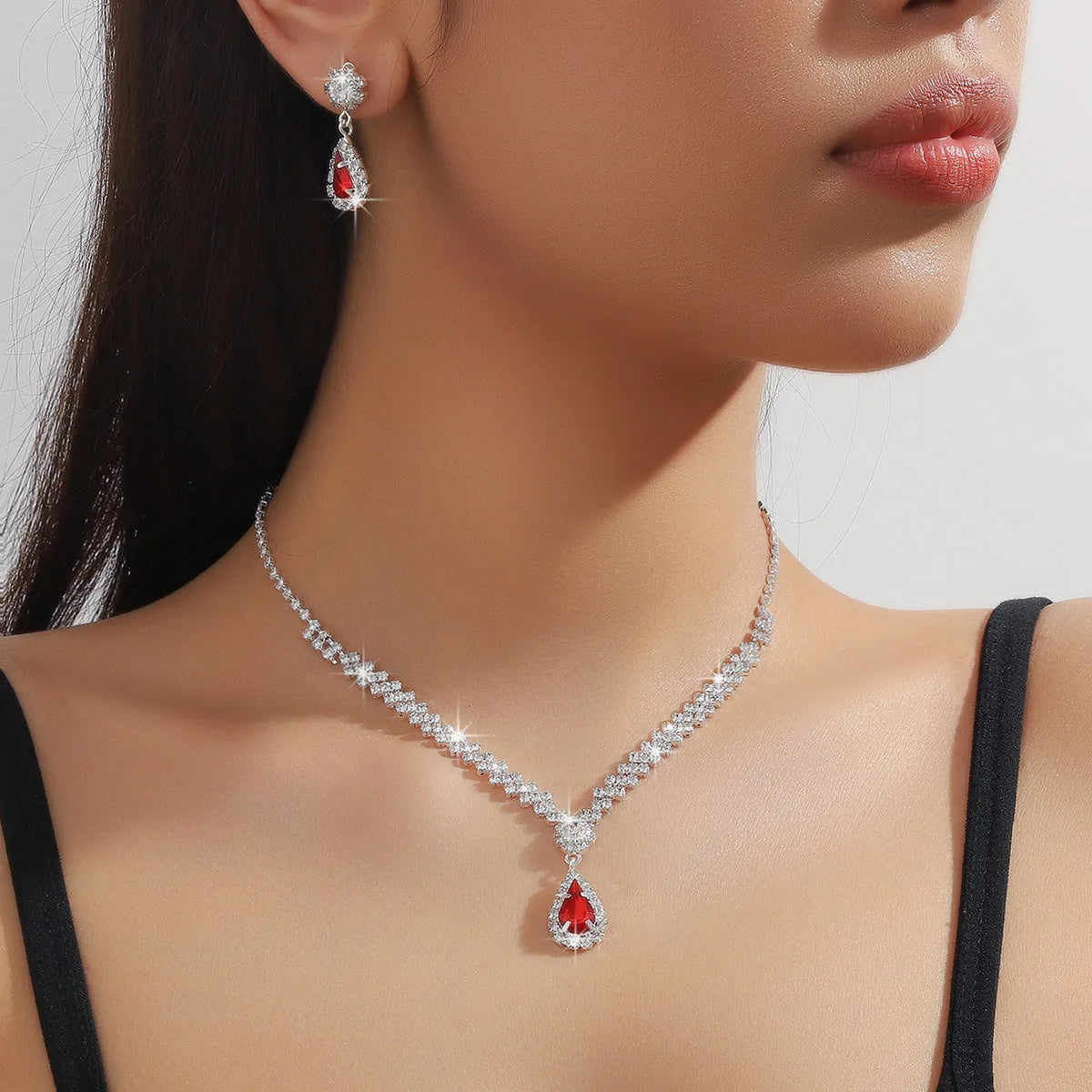 Women's blue claw chain necklace and drop rhinestone earrings set on white background.